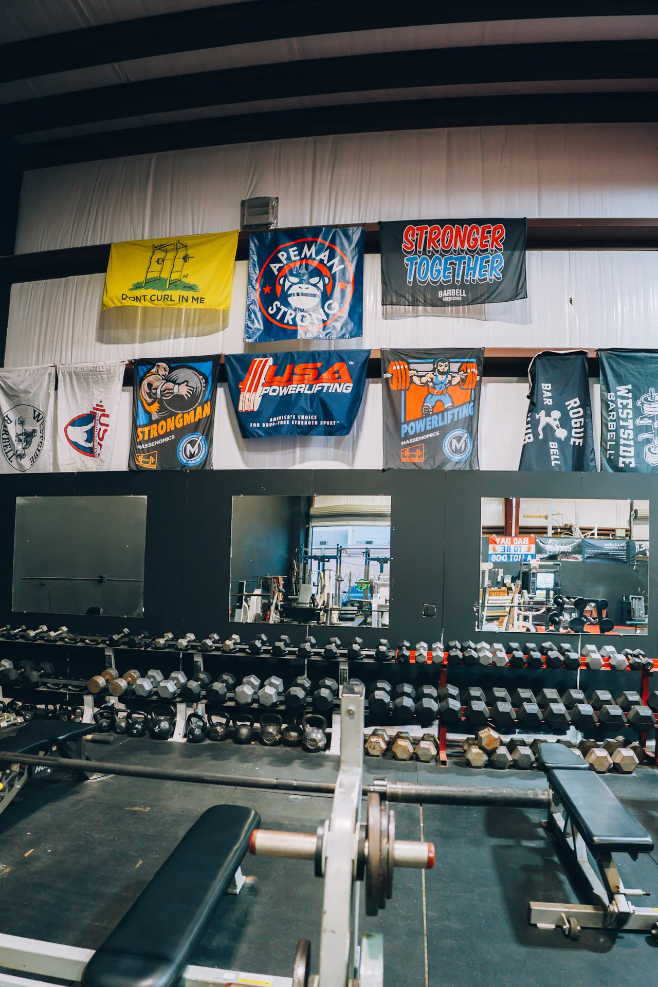 Dumbbells and benches in front of mirrors at Redline Barbell